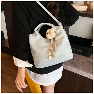 Detail of light blue faux crocodile bucket bag with plush bear and scarf on a model
