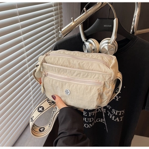 Detail of beige nylon crossbody bag featuring three zipper pockets and jacquard strap