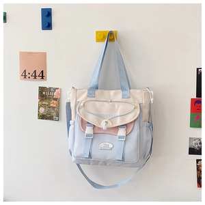 Detail of multi-color canvas tote bag featuring buckle pocket and brand patch detail