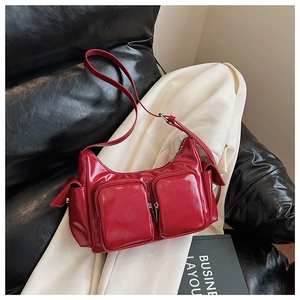 Detail view of glossy red motorcycle shoulder bag with multiple functional zippers and pockets