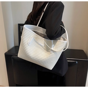 Macro shot of white woven tote bag showing detailed faux leather texture and brand logo
