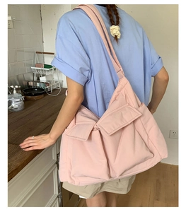 Detail of a large pink canvas shoulder bag with multiple utility pockets in a lifestyle setting