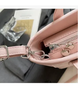 Close-up of pink lychee leather handbag with silver heart-shaped zipper and metal hook
