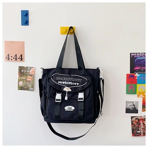 Detail view of black canvas tote bag featuring adjustable straps and buckle closures