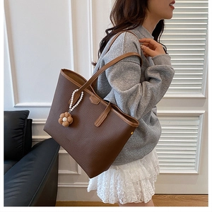 Vue détaillée du sac cabas en cuir marron avec breloque en perles et fleur décorative