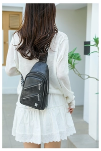 Rear view of model wearing a black leather chest bag with a wide zigzag patterned strap