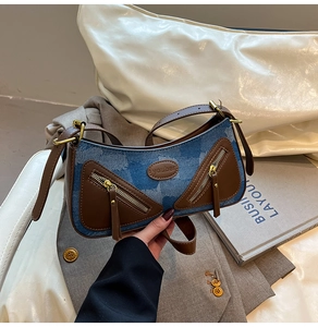 Close-up of vintage baguette bag featuring blue washed denim and brown leather accents