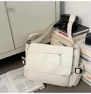 Detail of beige canvas messenger bag showing flap pocket and adjustable strap on books