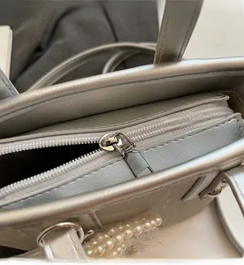 Macro detail of the smooth silver zipper and pearlescent texture on the bucket bag