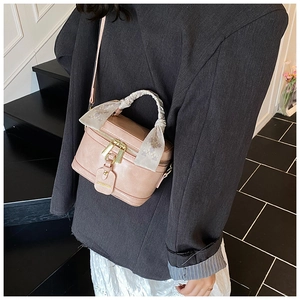 Détail d'un sac boîte rose avec anse en foulard de soie et étiquette ZARENZA sur modèle