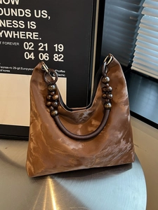 Brown marble pattern tote bag with vintage wooden bead handle on a silver metal table