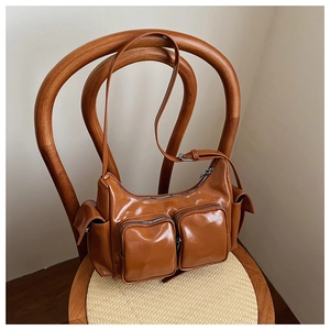 Close-up of caramel leather crossbody bag with multiple zip pockets on wooden chair