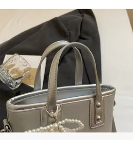Close-up of silver bucket bag cylindrical handles featuring elegant pearl pendant detail