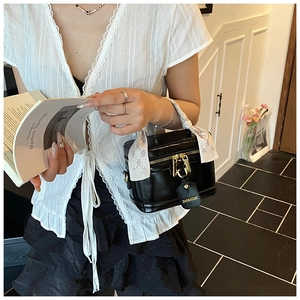 Détail d'un sac à main boîte noir avec poignée en soie et cadenas doré élégant