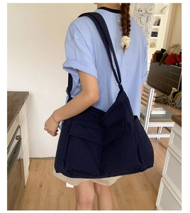 Detailed back view of a large navy blue canvas crossbody bag with dual utility pockets