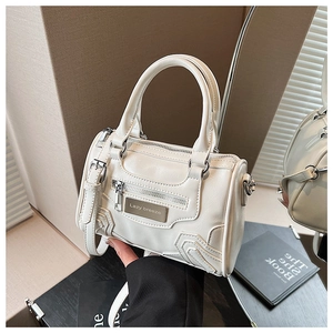 Detalle del bolso de cuero PU blanco con placa metálica y cremalleras decorativas modernas
