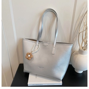 Détail du sac cabas argenté avec texture litchi et breloque fleur en perles
