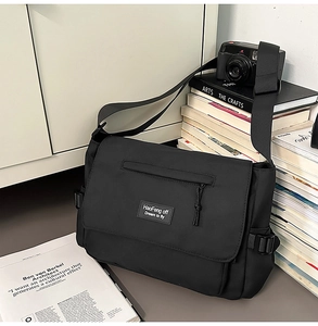 Detail of black nylon messenger bag with adjustable side buckle and front zipper pocket