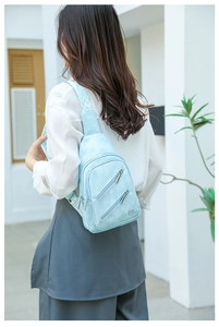 Detail of light blue chest bag with chevron strap and dual diagonal zippers for women