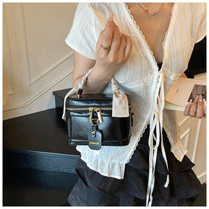Détail d'un sac boîte noir avec poignée en foulard de soie et fermetures éclair dorées
