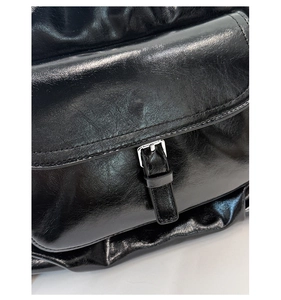 Nahaufnahme der glänzenden schwarzen Ledertasche mit silberner Schnalle und Textur