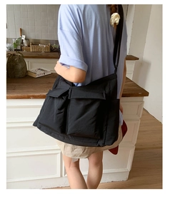 Detailed view of black canvas crossbody bag with dual front flap pockets and wide strap