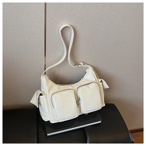 Detail view of a white glossy moon bag with multiple pockets and adjustable strap