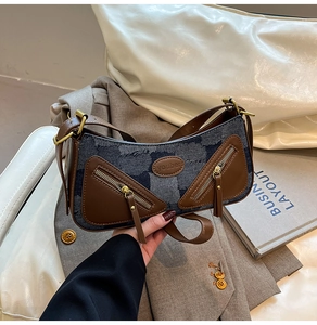 Detail of vintage patchwork denim crossbody bag with brown leather trim and metal zippers