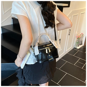 Détail du sac à main noir brillant avec anse en foulard de soie et détails dorés