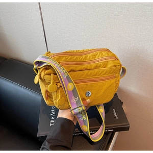 Detailed macro of bright yellow multi-pocket nylon crossbody bag with wide jacquard strap