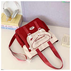 Detail of red and white canvas backpack with MondayLucy embroidery and side drawstring pocket