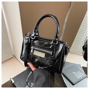 Detalle del bolso Boston negro brillante con placa de plata y acabado de laca suave