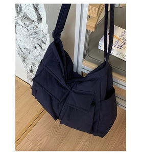 Close-up of a large navy blue quilted tote bag featuring two functional front pockets