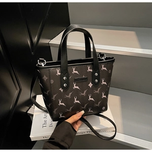 Détail du sac cabas noir avec imprimé cerf et rivets argentés sur des livres de design
