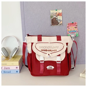 Detailed view of red canvas tote bag featuring white buckle closure and brand logo