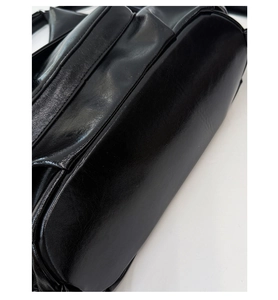 Detailansicht der glänzenden schwarzen Tasche mit Seitenreißverschluss und feinen Nähten