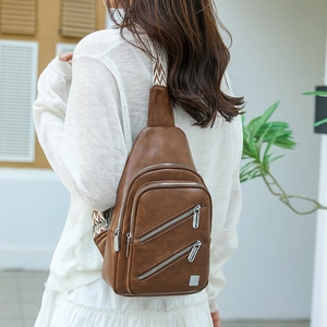 Brown PU leather chest bag detail showing double zippers and geometric pattern strap