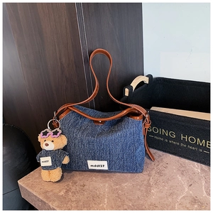 Detail of denim shoulder bag with brown faux leather trim and cute bear charm