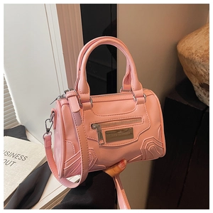 Detalle de bolso de mano rosa en piel PU con placa metálica y cremalleras de lujo