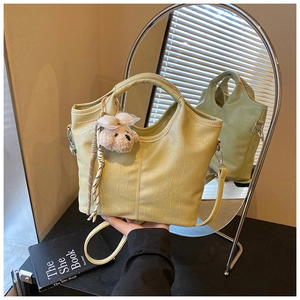 Detail of light green crocodile embossed bucket bag with a cute bear charm and shoulder strap