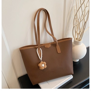 Détail d'un sac cabas marron foncé motif litchi avec chaîne perlée et breloque florale