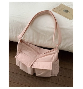Detail of light pink quilted canvas bag with large front pockets and wide shoulder strap