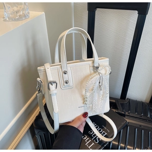 Detail of white tote bag with pearl bow charm and Fashion & Bags text on leather surface