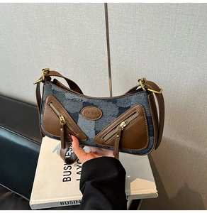 Detail of vintage denim baguette bag with brown leather pockets and gold metal zipper