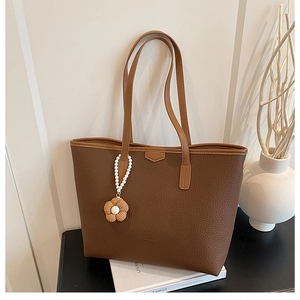 Détail du sac cabas marron à grain litchi avec breloque perle blanche et fleurie