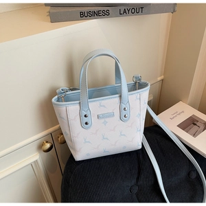 Vue détaillée du sac cabas bleu clair à motif de rennes avec plaque métallique sur tissu