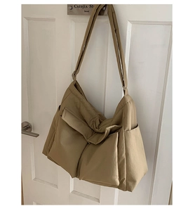 Detail view of khaki canvas tote with utility double front pockets on a white door