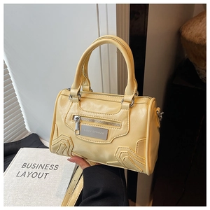 Primer plano detallado del bolso Boston en cuero amarillo brillante con placa de metal