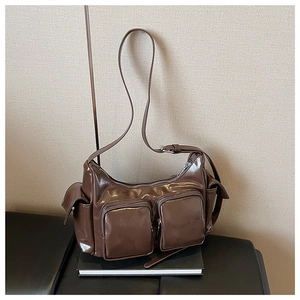 Detail of a brown glossy PU shoulder bag with functional multi-pocket utility design