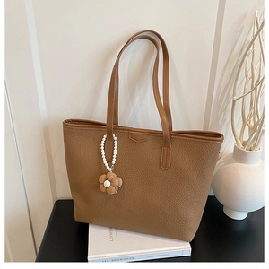 Détail d'un cabas marron texturé avec un pendentif décoratif en perles et fleurs